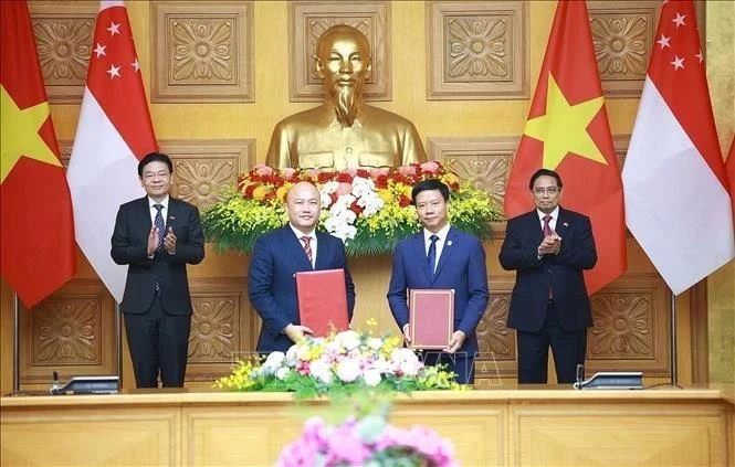 El primer ministro de Vietnam, Pham Minh Chinh (derecha), y su homólogo singapurense, Lawrence Wong (izquierda), presencian el intercambio del acuerdo de cooperación entre la Asociación de Amistad Vietnam-Singapur y la Fundación Internacional de Singapur. (Foto: VNA)