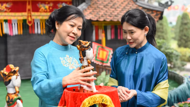Ngo Phuong Ly (izquierda), esposa del secretario general del Partido Comunista de Vietnam, To Lam, presenta una marioneta de agua a Loo Tze Lui, cónyuge del primer ministro de Singapur, Lawrence Wong. (Foto: VNA)
