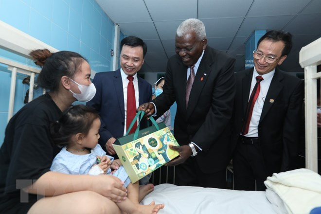 El presidente de la Asamblea Nacional del Poder Popular de Cuba, Esteban Lazo Hernández, regala un obsequio a una niña paciente en el hospital. (Fotografía: VNA)