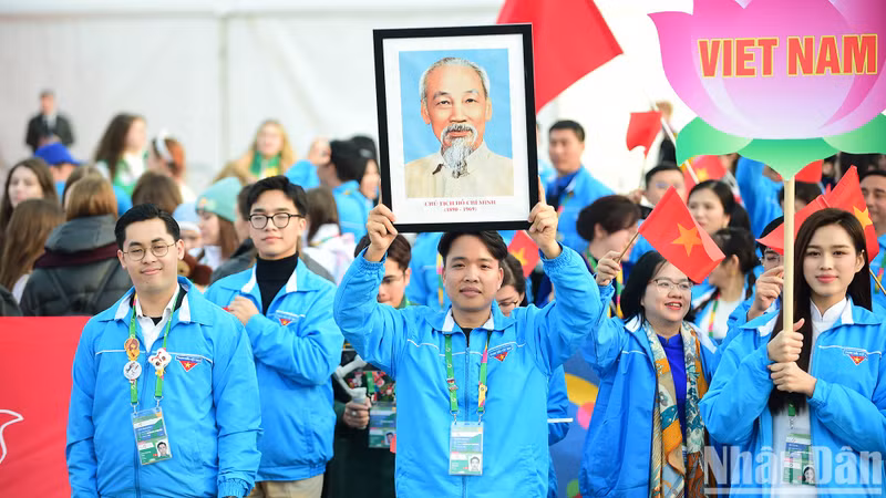 La delegación de Vietnam desfila con la camisa azul que identifica a la Unión de Jóvenes Comunistas Ho Chi Minh, banderas nacionales, foto de Ho Chi Minh y la bandera de la entidad.
