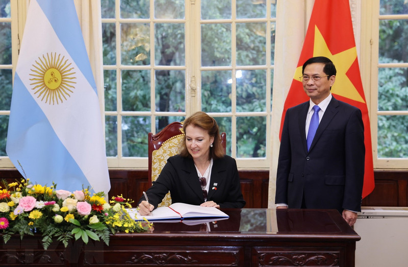 La ministra de Relaciones Exteriores, Comercio Internacional y Culto de Argentina, Diana Elena Mondino, escribe en un libro de visitas sobre el testimonio del ministro de Relaciones Exteriores, Bui Thanh Son. (Fotografía: VNA)