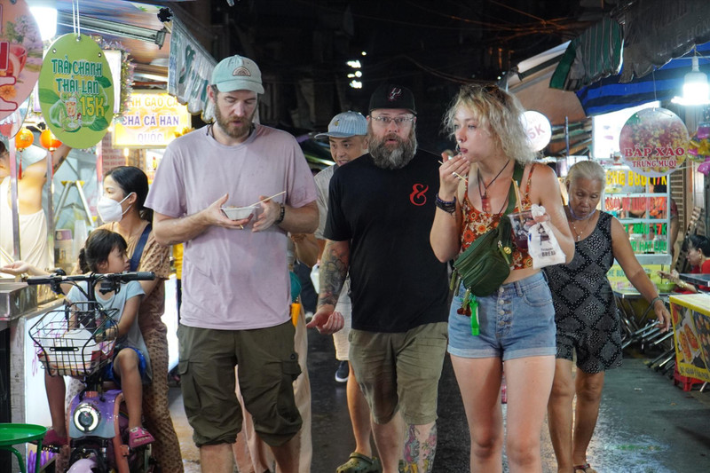 Turistas extranjeros disfrutan de la gastronomía nocturna en Ciudad Ho Chi Minh.