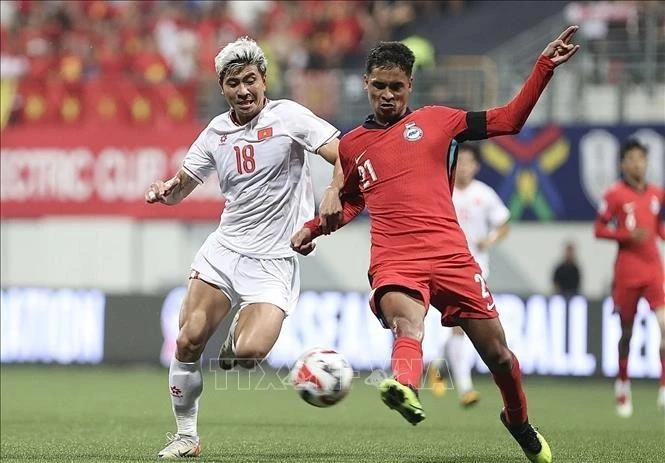 El futbolista Thanh Binh (camiseta blanco) fue bloqueado ferozmente por un defensor de Singapur en el partido de ida de la semifinal de la Copa de la Asean el 26 de diciembre. (Foto: VNA)