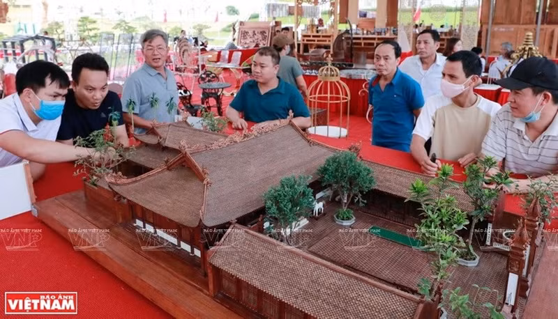 Visitantes disfrutan del modelo del templo comunal de madera más pequeño de Vietnam. (Fuente: VNA)