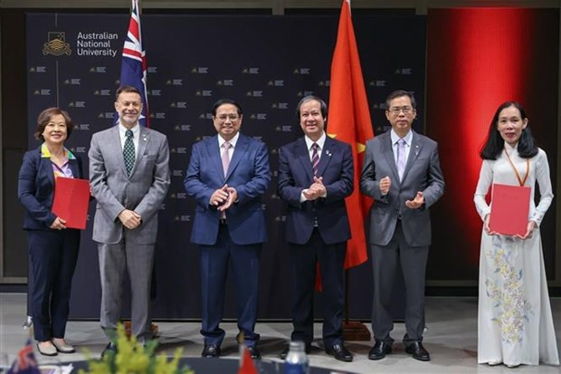 El primer ministro de Vietnam, Pham Minh Chinh (tercera persona desde la izquierda), presencia la entrega de documentos de cooperación en materia de educación entre universidades vietnamitas y australianas. (Foto: VNA)