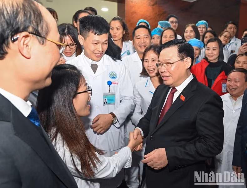 El presidente de la AN, Vuong Dinh Hue, con médicos y las enfermeras del Hospital General del distrito de Dinh Hoa.
