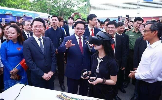 El primer ministro Pham Minh Chinh y otros delegados visitan las áreas de exhibición que presentan productos innovadores y de transformación digital de universidades y empresas. (Foto: VNA)