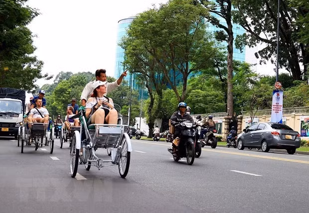 Los turistas extranjeros visitan el centro de Ciudad Ho Chi Minh en ciclo. (Fotografía: VNA)