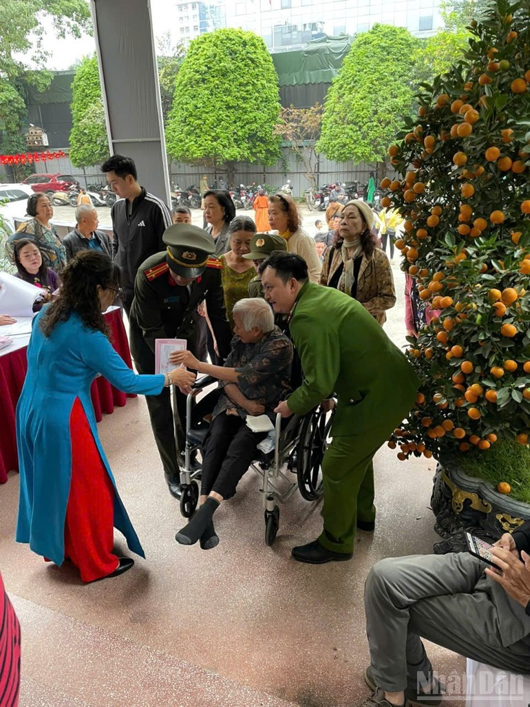 Voluntarios ayudan a un anciano en sillas de rueda en la zona de votación.