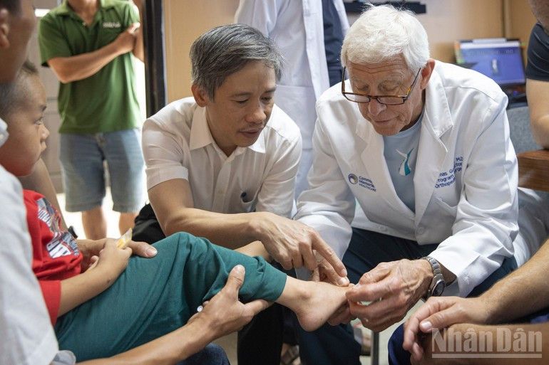 El profesor asociado y doctor Nguyen Manh Khanh, vicedirector del Hospital de Amistad Vietnam-Alemania, presidente de la Asociación de Traumatología y Ortopedia de Vietnam y presidente del club Sala, examina a un habitante de la zona junto con un colega estadounidense.