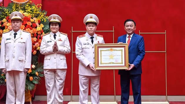 El miembro del Buró Político y permanente del PCV, Tran Cam Tu, entrega el título de Héroe de las Fuerzas Armadas Populares a la Fuerza de Seguridad Interna.