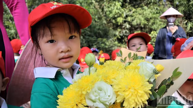Los niños llevan hermosos ramos de flores para ofrecer al querido Tío Ho.