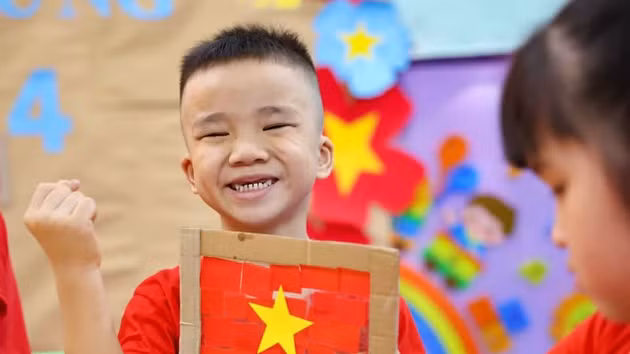 Niños vietnamitas entusiastas con taller de creación de la bandera nacional