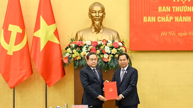El secretario del Comité del Partido Comunista de Vietnam en la Asamblea Nacional y presidente de esta, Tran Thanh Man (izquierda), entrega la decisión del Buró Político del Comité Central del Partido a Le Quang Manh.