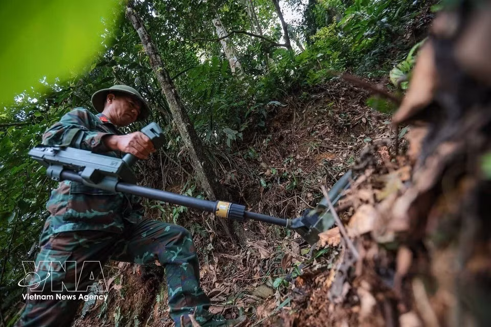 Uso de detectores para la localización y neutralización de minas, municiones y otros artefactos explosivos remanentes de la guerra en la zona de búsqueda y recuperación de los restos de mártires. (Foto: VNA)