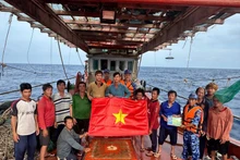 Las fuerzas de seguridad marítima de Ciudad Ho Chi Minh entregan la bandera nacional y difunden medidas preventivas contra la pesca INDNR a los marineros. (Foto: VNA)