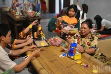La artesana Nguyen Thi Tuyen presenta muñecos del “doctor de papel” a los jóvenes.
