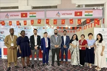 El consejero comercial Bui Trung Thuong (cuarto desde la izquierda) posa para una foto con invitados nacionales e internacionales que visitan el stand. (Foto: VNA)