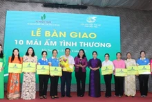 Una representante del periódico Nhan Dan entrega una placa simbólica de diez casas de caridad a las mujeres en situación difícil de la localidad. (Foto: HOANG TRUNG)