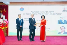 La profesora asociada y doctora Nguyen Thi Lien Huong, viceministra de Salud, entrega la Medalla Conmemorativa “Por la Salud del Pueblo” a expertos del JIHS.