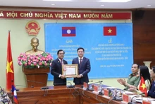 Por autorización del Primer Ministro del Gobierno laosiano, el compañero Leklai Sivilay otorga la Orden de Trabajo de primera clase del Gobierno laosiano a Nguyen Dinh Trung, secretario del Comité del Partido Comunista de Vietnam en Dak Lak. (Fotografía: Nhan Dan)