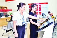 Funcionarios del Centro de Servicios Administrativos Públicos del barrio Hong An, en la ciudad de Hai Phong, ayudan a los ciudadanos a presentar los expedientes en línea. (Foto: TRUNG KIEN)