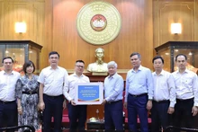 Do Van Chien, miembro del Buró Político y del Secretariado del Comité Central del Partido Comunista y presidente del Comité Central del Frente de la Patria de Vietnam, recibe el donativo de Nhan Dan. (Foto: Nhan Dan)
