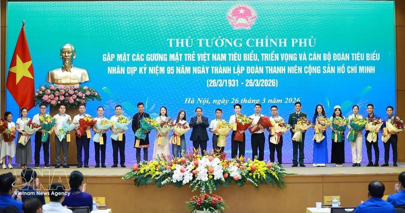 El primer ministro Pham Minh Chinh entrega flores para felicitar a los jóvenes vietnamitas destacados. (Foto: VNA)