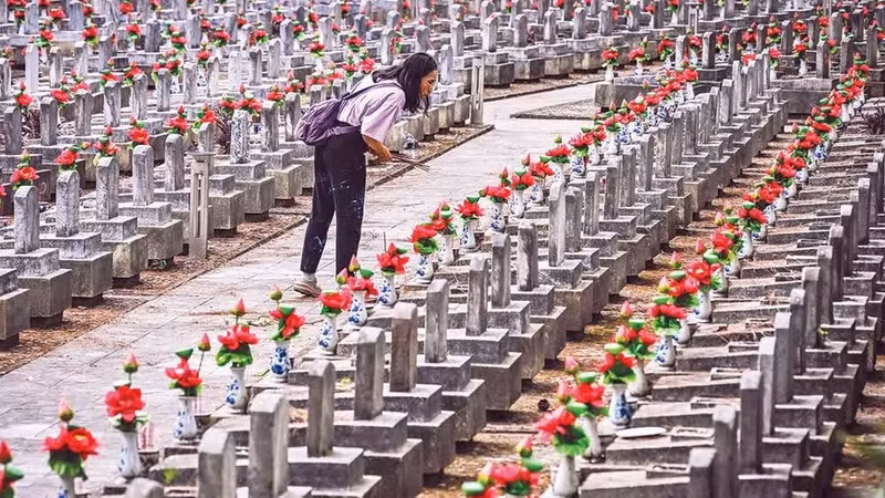 Una joven busca el nombre de su padre entre miles de lápidas.