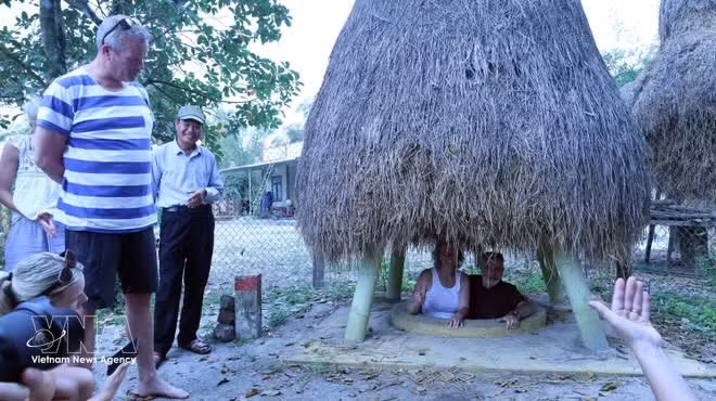 Los turistas suben por una entrada de túnel situada en el jardín de una casa en el túnel de Ky Anh. (Foto: VNA)