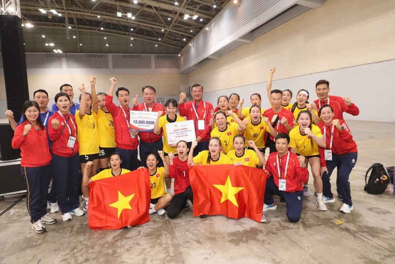 Las jugadoras y el cuerpo técnico de la selección femenina vietnamita de balonmano celebran su medalla de oro. (Foto: VNA)