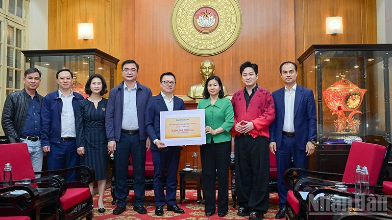 El presidente-editor del periódico Nhan Dan, Le Quoc Minh, entrega la asistencia a las víctimas de las inundaciones.