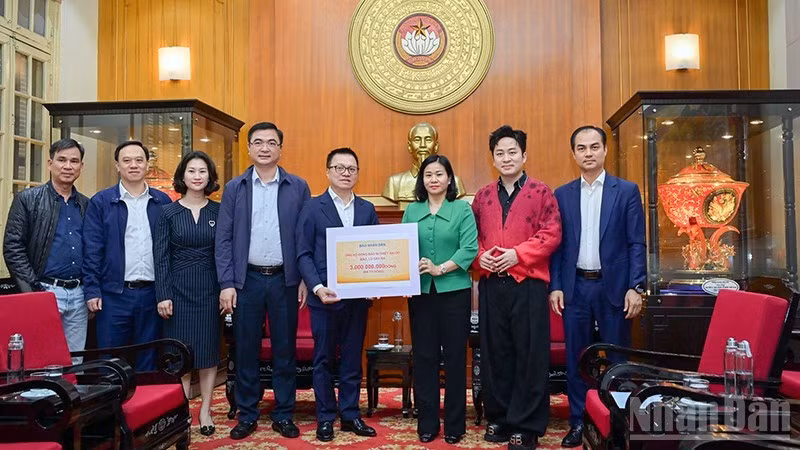 El presidente-editor del periódico Nhan Dan, Le Quoc Minh, entrega la asistencia a las víctimas de las inundaciones.