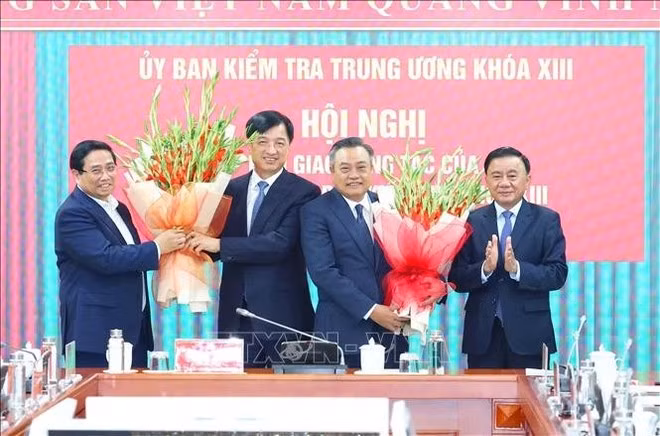 El primer ministro Pham Minh Chinh, y el miembro permanente del Secretariado, Tran Cam Tu, entregaron flores para fecilitar a los compañeros Tran Sy Thanh y Nguyen Duy Ngoc. (Foto: VNA)