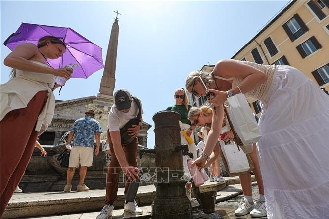 La gente bebe agua para refrescarse en un día caluroso en Roma, Italia. (Foto: Xinhua/VNA)
