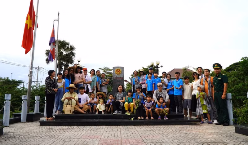Antes de vivir la experiencia en los campos inundados, los turistas visitan y toman fotos conmemorativas en el hito fronterizo nacional del Paso Internacional de Thuong Phuoc (comuna de Thuong Phuoc). (Foto: VNA)