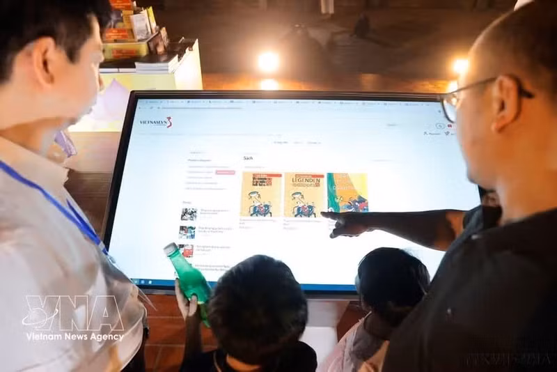 Los visitantes prueban la aplicación de libros electrónicos. (Foto: VNA)