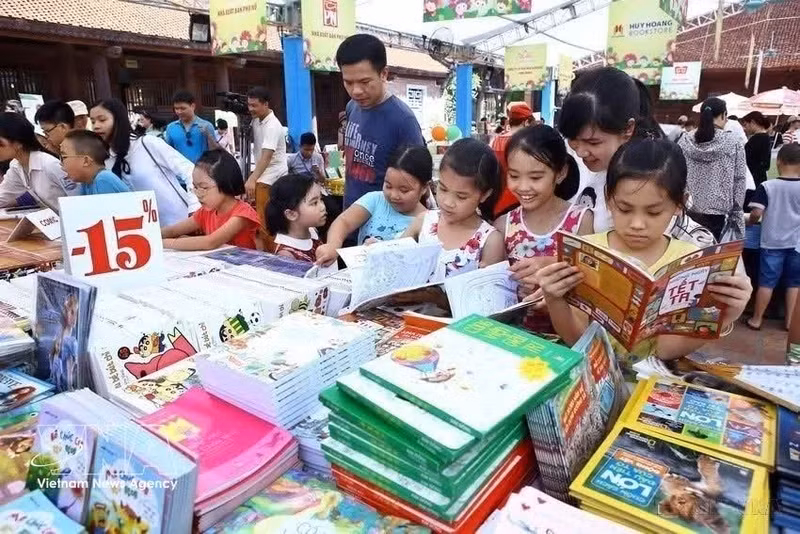 Los niños eligen con entusiasmo sus libros favoritos junto a sus familias en una feria. (Foto: VNA)