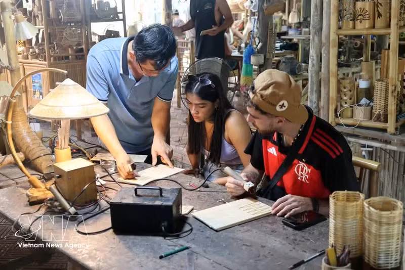 Los turistas participan en la elaboración de diseños en bambú en un lugar turístico del barrio de Hoi An Dong, en Da Nang. (Foto: VNA)