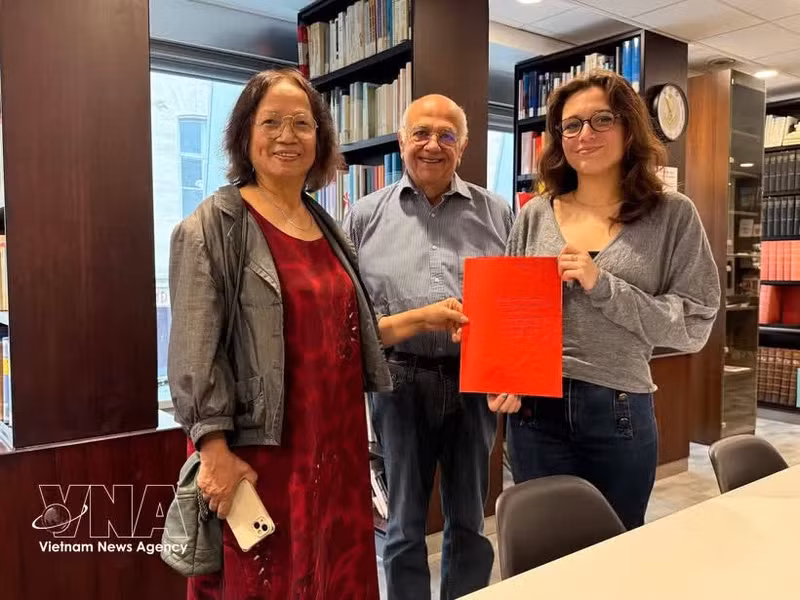 La investigadora cultural Tran Thu Dung (izquierda), Yonnel Ghernaouti, miembro de la Junta Directiva del Instituto Masónico de Francia, y Emma Lallemand, bibliotecaria del GODF, posan para una fotografía con documentos de archivo sobre Nguyen Ai Quoc. (Foto: VNA)