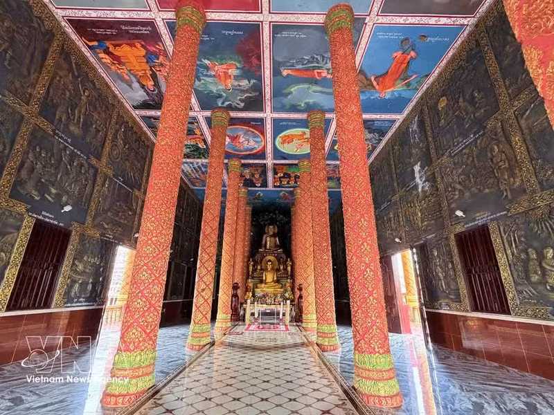 En el interior del santuario principal, dos hileras de enormes columnas sostienen el techo del templo, creando un espacio amplio, ventilado y fresco. Las paredes y el techo están cubiertos de elaborados relieves y coloridos murales que recrean vívidamente la vida de Buda, desde su nacimiento hasta su camino espiritual hacia la iluminación. (Foto: VNA)