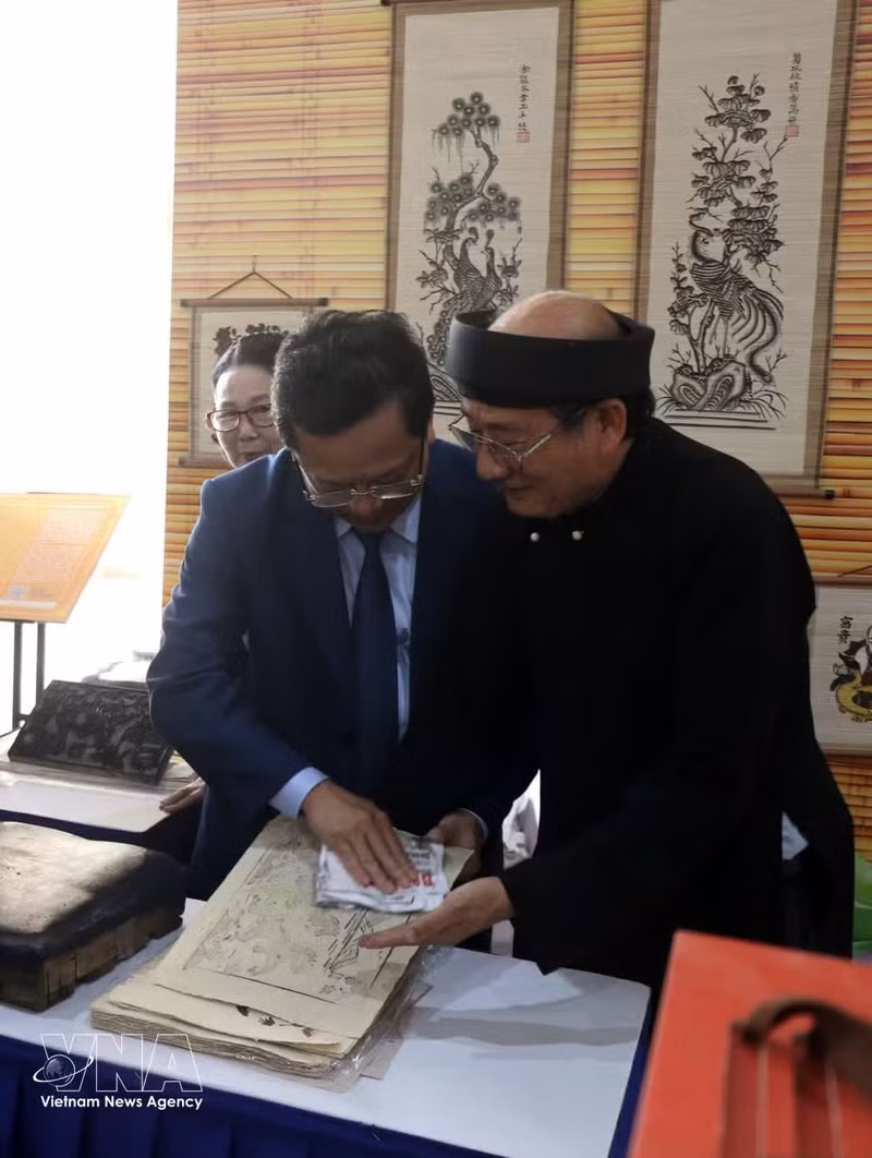 El artesano Nguyen Huu Hoa presenta la esencia de la pintura popular Dong Ho a los visitantes. (Foto: VNA)