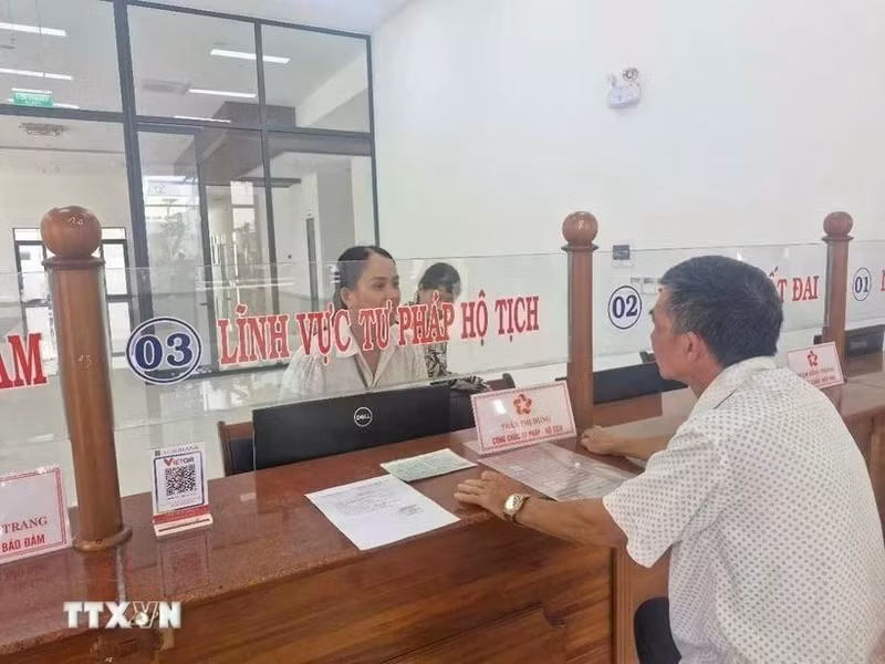 Las personas hacen trámites administrativos en el día del inicio de la prueba del gobierno de dos niveles en el distrito de Pleiku, Gia Lai. (Foto: VNA)
