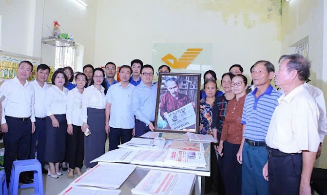 Le Quoc Minh, presidente-editor de Nhan Dan, entrega un cuadro del tío Ho leyendo el periódico Nhan Dan a los cuadros, miembros del Partido y habitantes de la comuna de Tan Hung en la oficina de correo y centro cultural de la comuna de Tan Hung.