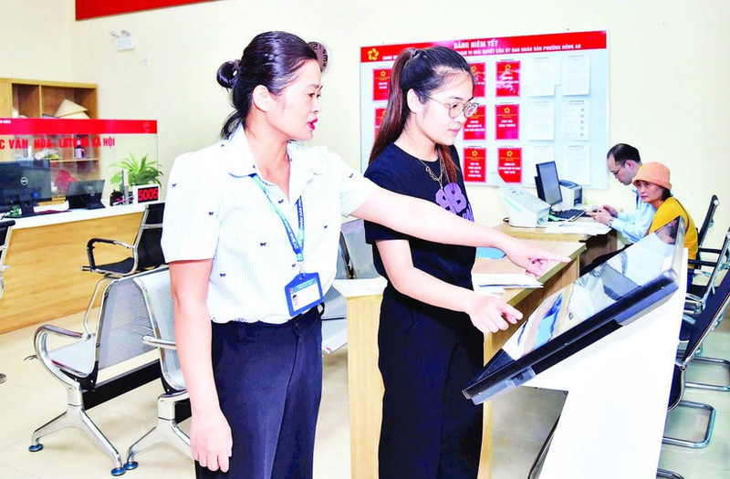 Funcionarios del Centro de Servicios Administrativos Públicos del barrio Hong An, en la ciudad de Hai Phong, ayudan a los ciudadanos a presentar los expedientes en línea. (Foto: TRUNG KIEN)