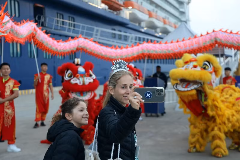 Los turistas del Celebrity Solstice disfrutan tomándose fotos con un equipo de danza del león y el dragón. (Foto: VNA)