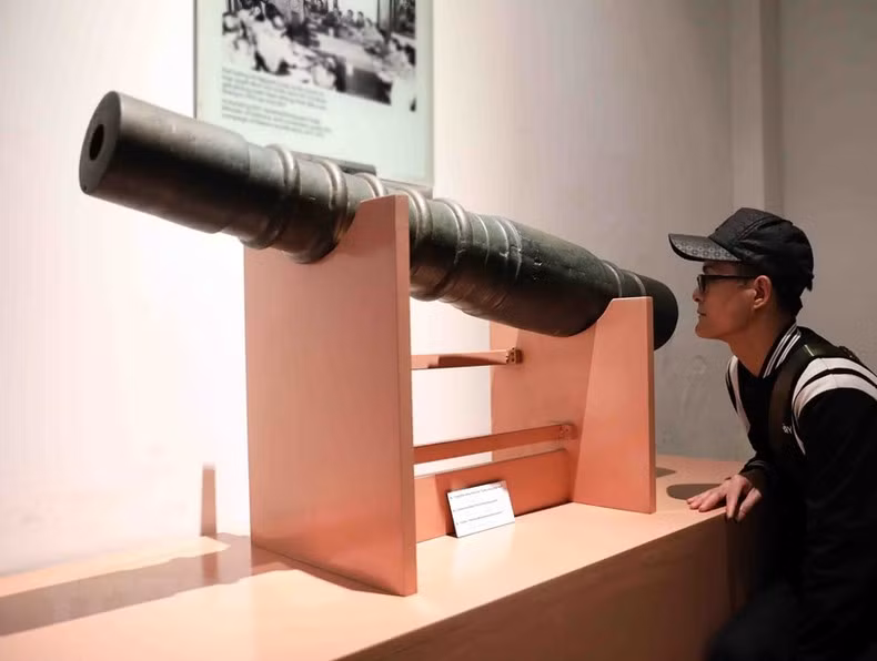 Visitante observa el cañón de la época Le Trung Hung.