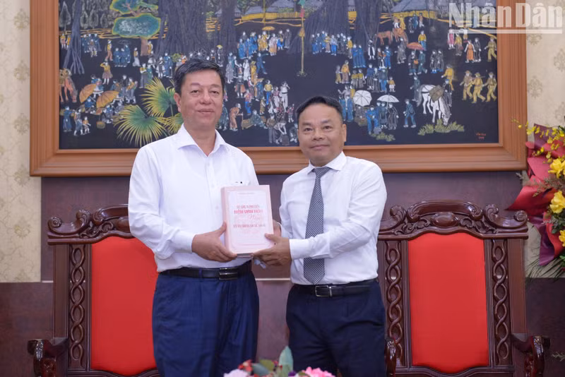Trong Lam entrega un libro publicado por la Editorial a Dinh Nhu Hoan, redactor jefe adjunto de Nhan Dan.