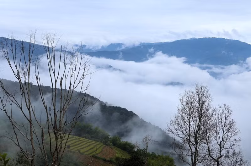 Las blancas nubes cubren los campos de terrazas que se entrelazan con majestuosas montañas.