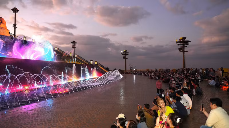 Los visitantes disfrutan de un espectáculo de fuentes danzantes iluminadas de colores vibrantes en la cima de la montaña Ba Den, creando un ambiente animado e impresionante. Los visitantes disfrutan de un espectáculo de fuentes danzantes iluminadas de colores vibrantes en la cima de la montaña Ba Den, creando un ambiente animado e impresionante.